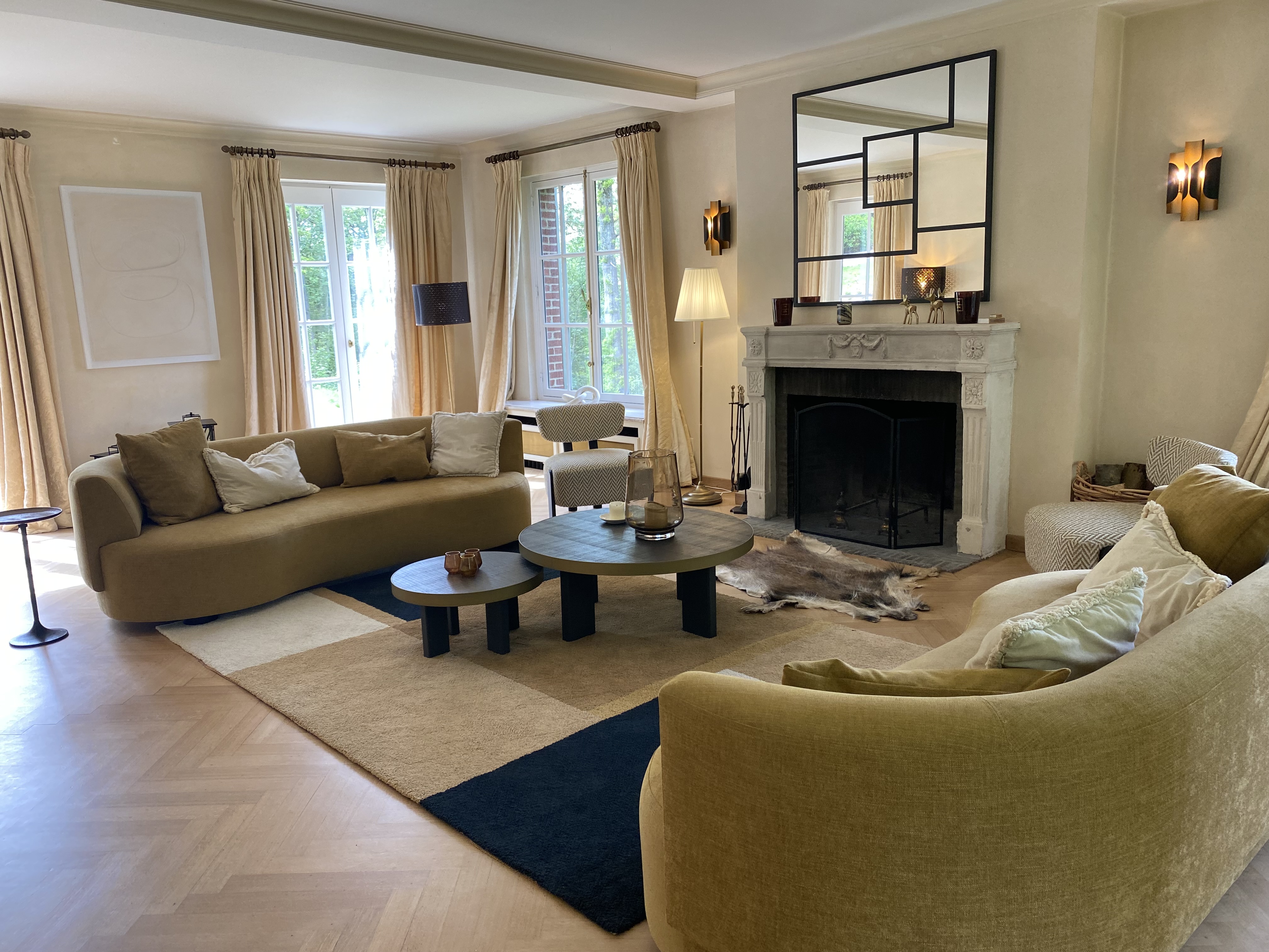 Salon contemporain avec canapés incurvés, cheminée et parquet en chevrons
