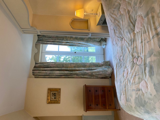 Chambre classique avec lit, commode en bois et vue sur le jardin