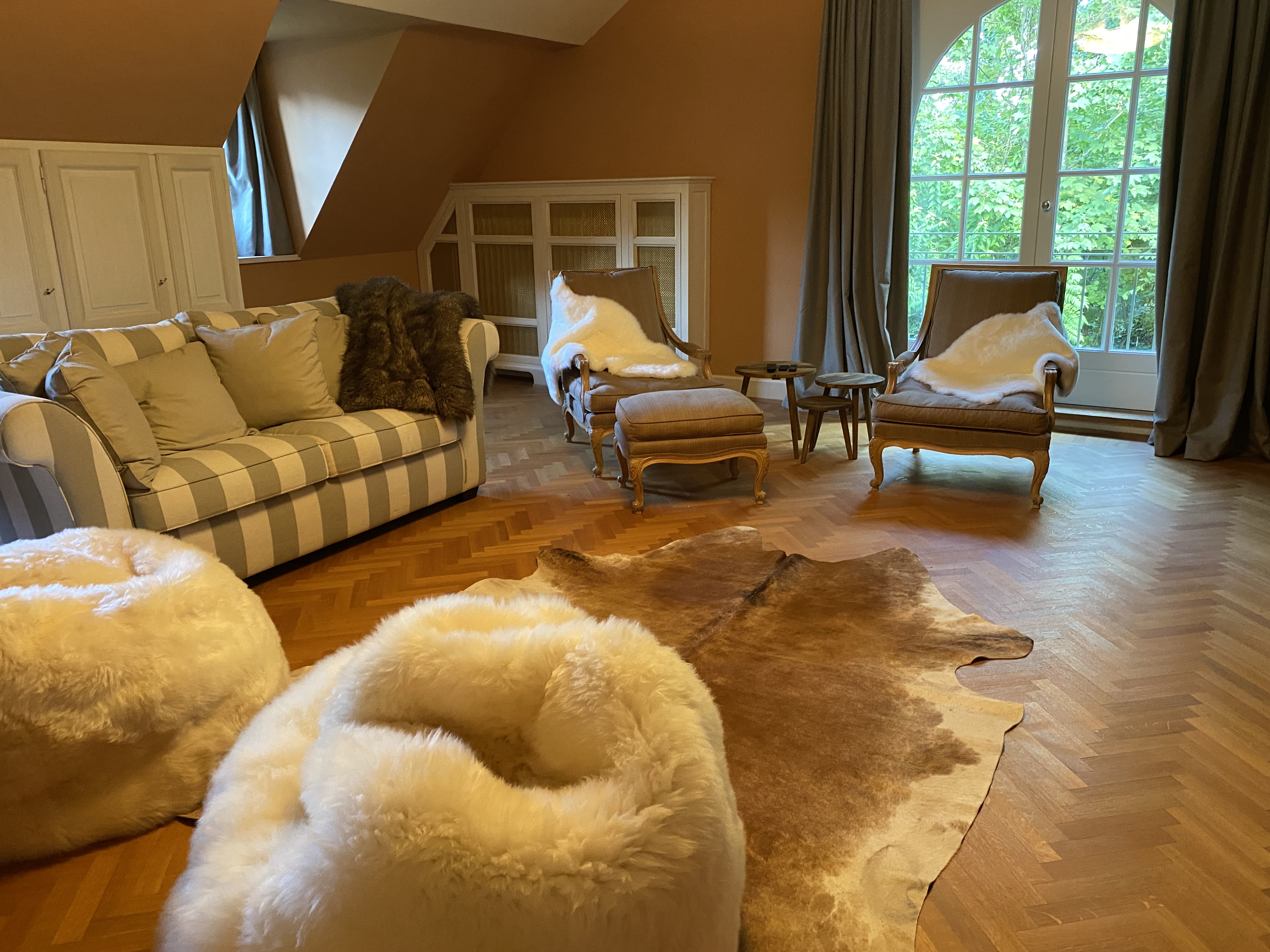 Salon cosy avec canapé rayé, fauteuils classiques et poufs blancs
