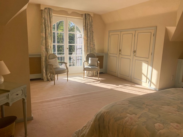 Chambre lumineuse avec deux fauteuils devant une grande fenêtre arquée