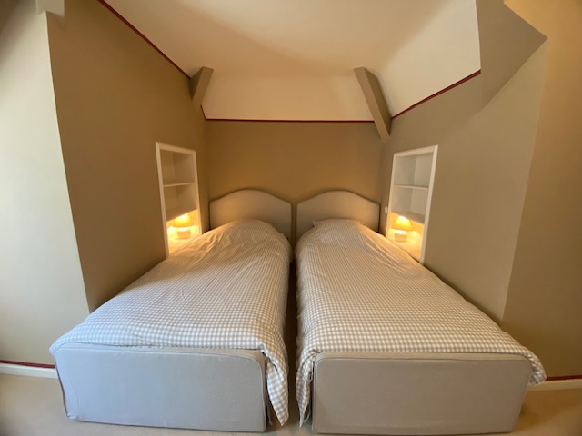 Chambre avec deux lits simples et étagères intégrées éclairées
