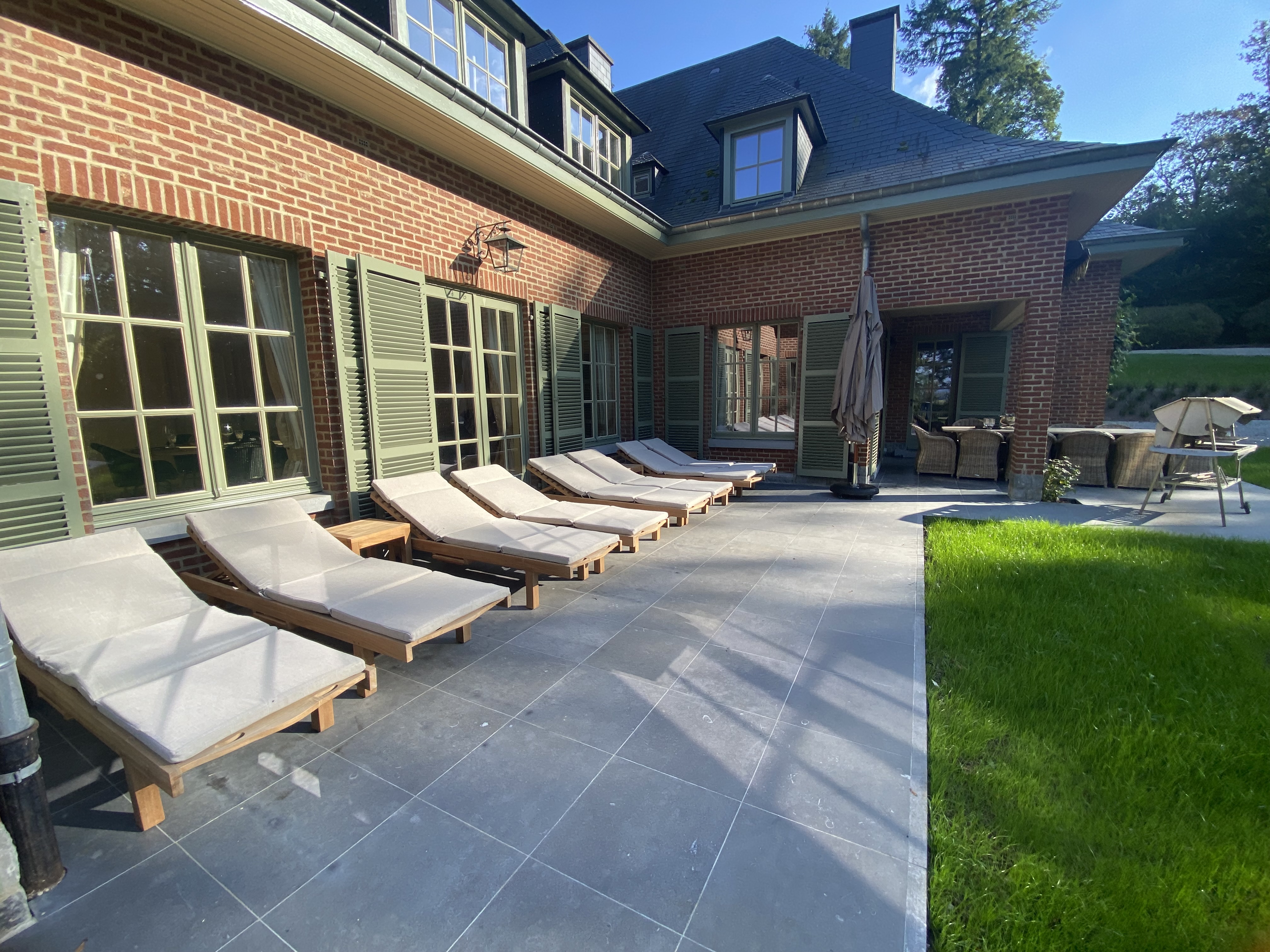 Terrasse avec transats, coin repas couvert et barbecue