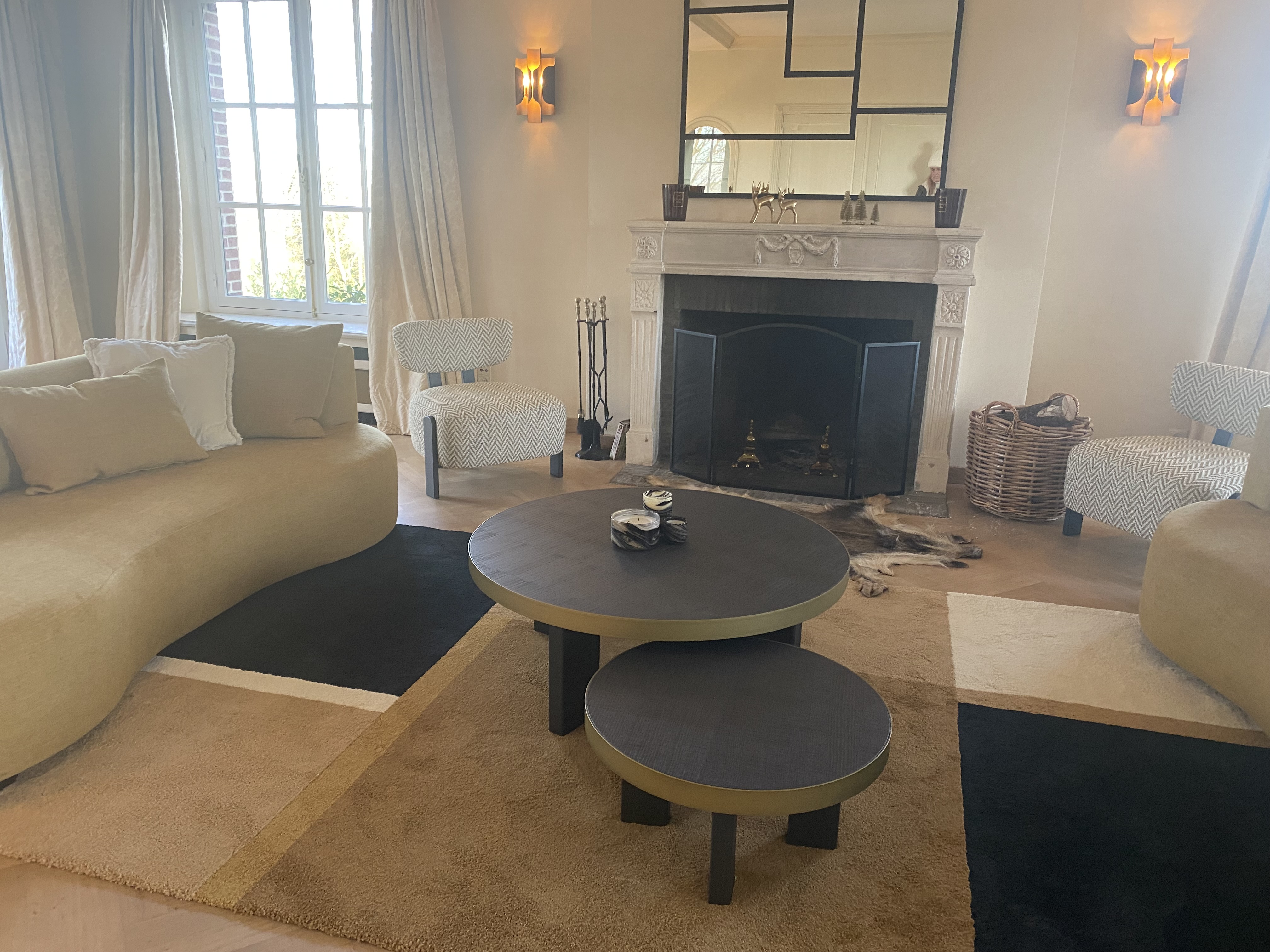Salon chaleureux avec cheminée, canapé incurvé et fauteuils à motifs